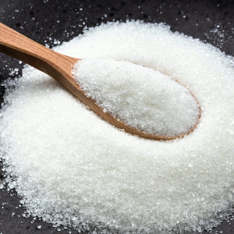 wooden spoon with white refined sugar on black wooden spoon with white refined sugar on black